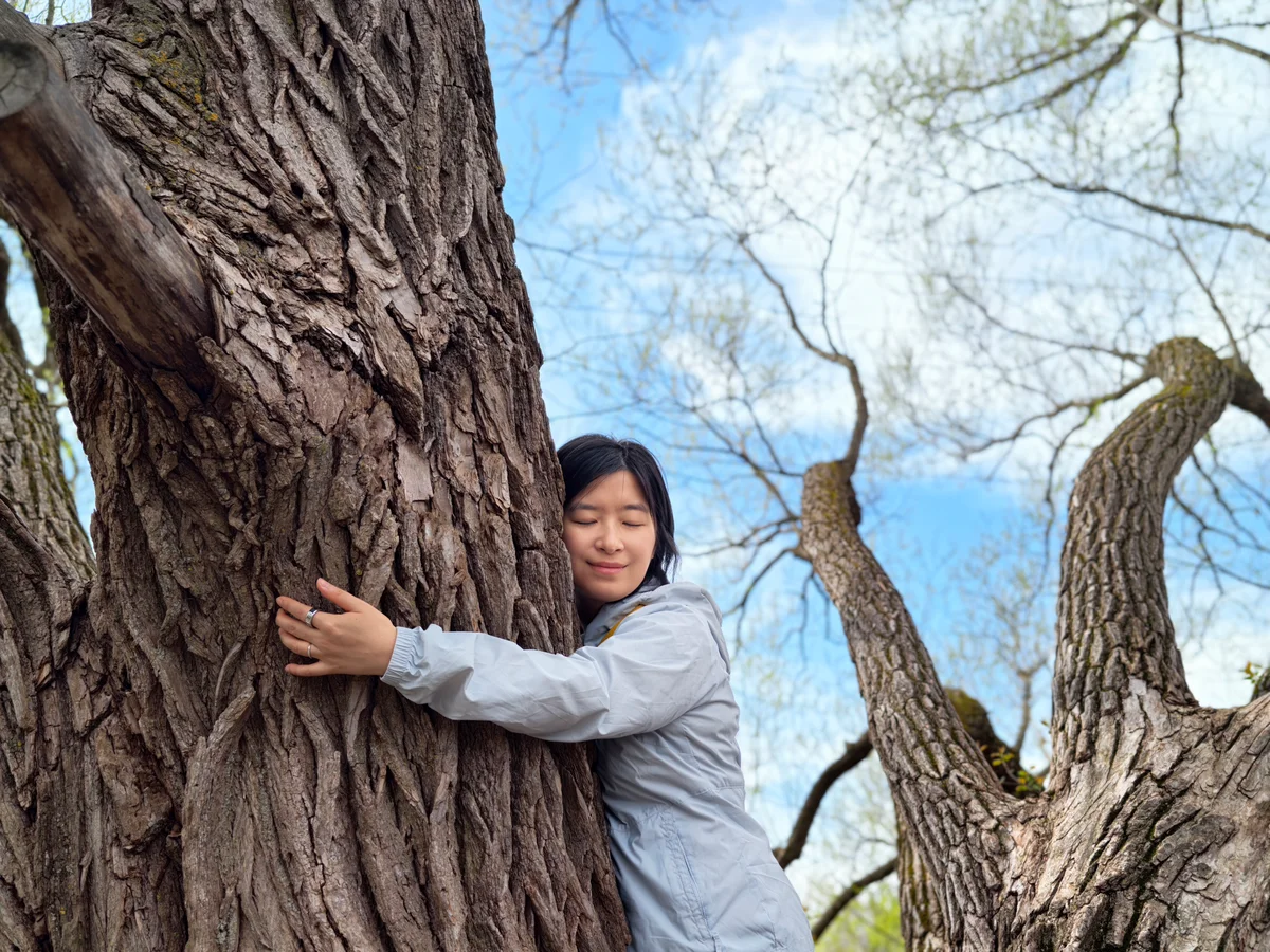 Songqin standing beside a tree outdoors